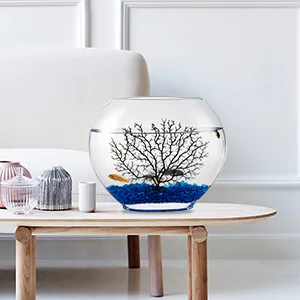 Modern glass fishbowl with blue gravel, decorative tree, and yellow fish on wooden table