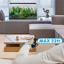 Person using remote control to operate Hygger aquarium with 32ft max range, showing fish tank in modern living room setting