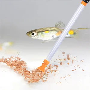 A small fish swims near a feeding tube with orange pellets on a white background, showcasing aquarium feeding.