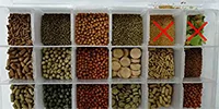 Aquarium fish food selection with various pellets, flakes, and seeds in a grid layout, highlighting different types for fish