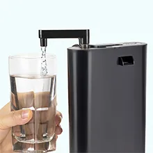 A hand holding a glass of water being filled by a modern black water dispenser with a sleek design.