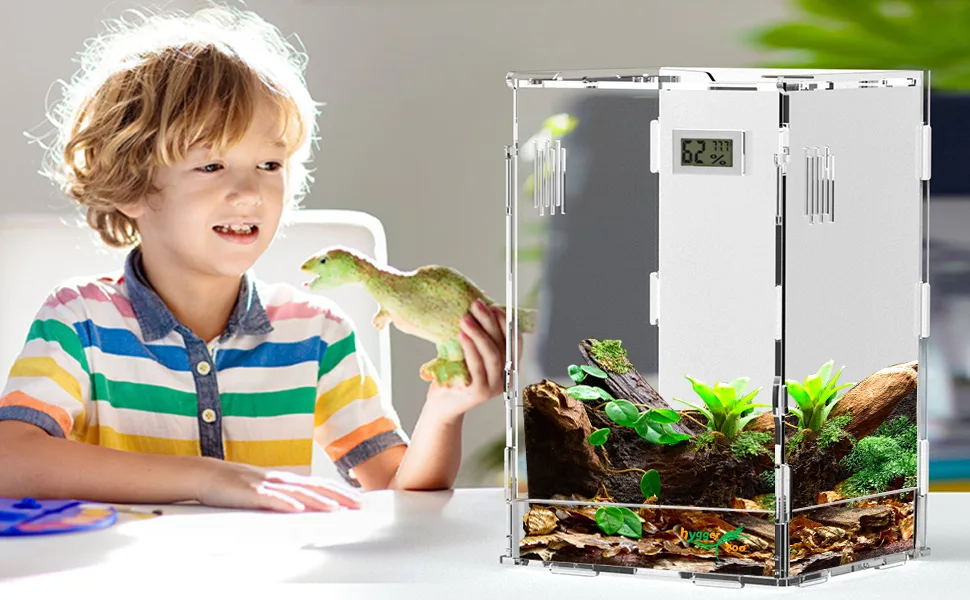 A child holding a dinosaur toy next to a transparent hygger aquarium with plants and rocks, showing a digital temperature dis