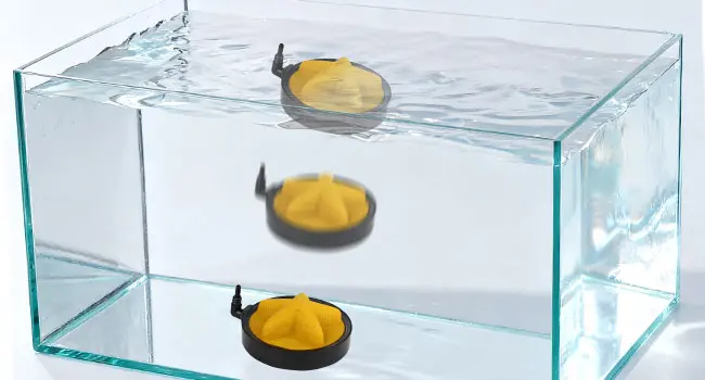 Three yellow and black hygger aquarium floats floating in clear water inside a glass tank, demonstrating water level control.