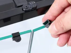 Hand holding green aquarium tubing with black connectors attached to a metal frame