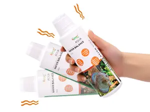 Hand holding Hygger Aquarium water conditioner bottles with orange labels and green packaging, showing product details for aq